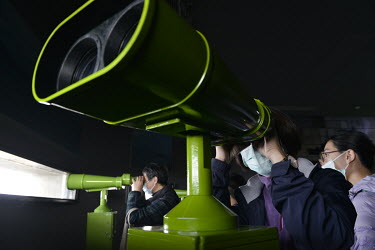 Taiwanese domestic tourists look at the coast of the Chinese mainland, just a few miles away, through high-powered binoculars at a military outpost on Xiao (Little) Kinmen.  Following the retreat of C...