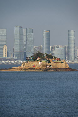 Shiyu Islet, a forward observation post controlled by the Taiwanese military, and the gleaming skyscrapers of Xiamen on the Chinese mainland beyond, seen from Xiao (Little) Kinmen Island.  Following t...