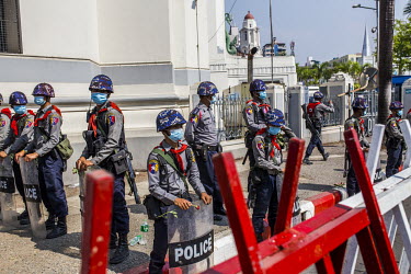 Police officers stand behind barricades, guarding a building in Yangon during protests against the military coup. On 1 February 2021, the military seized power, deposing the democratically elected gov...