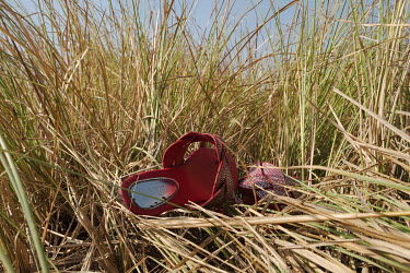 Helina Korley's shoes lie in long grass on the edge of the 'Yomo', the area traditionally held to be the spiritual heart the Songor Lagoon. Tradition dictates that shoes may not be worn in this part o...
