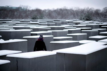 A vistor walks through snow that has fallen on the Stele of the Holocaust Memorial.
