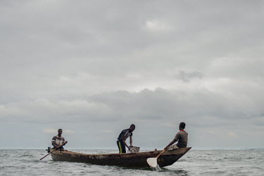 Vincent (14, left) and Noah Oletey (12), together with boat pilot Jonas Asideka, setting fish traps in Lake Volta an hour offshore of the village of Kpando Torkor.  Brothers Vincent and Noah spend up...