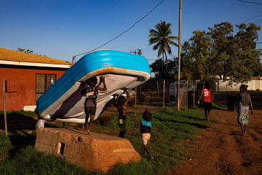 Children carry a blow up swimming pool to a neighbouring house. Wadeye is very hot most of the year with most days registering over 30 degrees Celsius with very high humidity especially in summer.