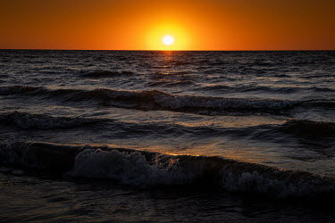 The sun sets over a beach on the Timor Sea.