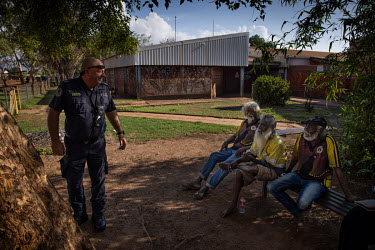 Paul Jones, sergeant at the Wadeye Police Station, talks with a group of Aboriginal elders as he walks around the Wadeye. In a town where very little traditional policing occurs (many of the cases are...
