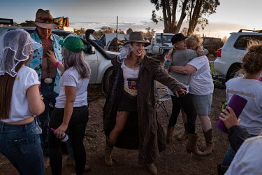 A bride-to-be (centre), who is having her hen party during the Ariah Park Bachelor and Spinster ball, dances in the hen party's campsite.   Known to locals as simply B&S balls, the events are held r...