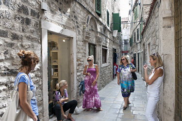 Female shopkeepers gather outside their premises to talk and smoke in a narrow alley inside the complex of the Palace of Diocletian.