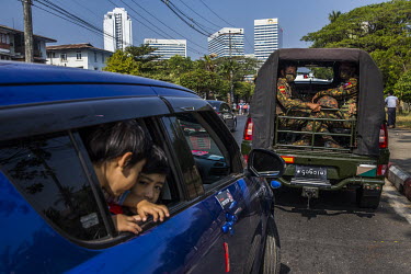 Children look out from the window of a car parked beside a military truck full of soldiers as nearby tens of thousands of people gathered in front of the Central Bank to protest against the military d...