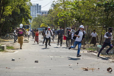 Anti-coup protestors scatter as security forces fire live rounds and tear gas towards them.