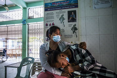 Wai Lin Tun (18) a protestor who was beaten around the head with batons by security forces lies on his mother's lap while waiting to be treated at a social centre treating injured protestors.