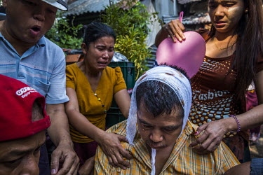 Family and neighbours help U Thein Htay who was beaten up by a group of pro-military supporters including monks that came into their neighbourhood armed with swords and sticks and attacked local resid...