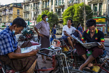 Trishaw drivers read newspapers and chat about politics.