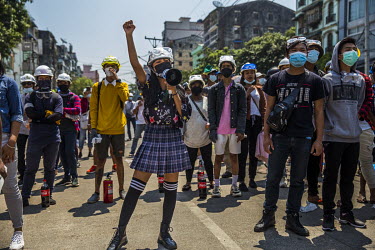A young woman leads chants as youth protestors demonstrate against the military coup. Around her protestors have bottles of Coca-Cola to use to treat the effects of tear gas.