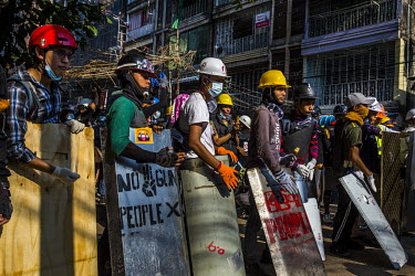 Youth protestors wearing hard hats stand behind homemade shields as they prepare to defend themselves as police and military joint security forces move forward to crack down on the anti-coup demonstra...