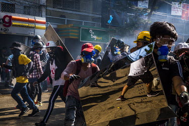 Youth protestors, wearing hard hats and carrying homemade shields, try to defend themselves as police and military joint security forces move forward in a violent crack down on anti-coup demonstration...