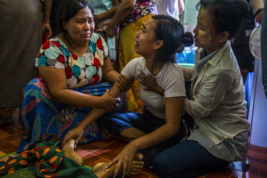 Ma Aye Chan Myint is comforted by family members as she cries beside her dead husband Ko Chit Min Thu (25). He was shot in the head with live ammunition fired by security forces while trying to protec...