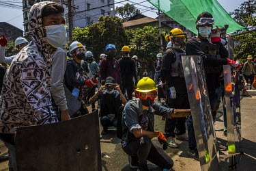 Youth protestors wearing hard hats and some holding homemade shields stand by to defend themselves as police and military joint security forces move forward to crack down on the anti-coup demonstratio...