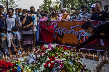 People holding candles kneel and pray beside a tribute of flowers at the site where anti-coup protestor Ko Chit Min Thu (25) was shot in the head and killed with live ammunition fired by security forc...