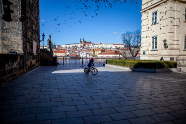 A child on a bicycle near the start of the Charles Bridge (left) with Prague Castle in the background. On 1 March 2021 the state of emergency lockdown in the Czech Republic was reinstalled because of...