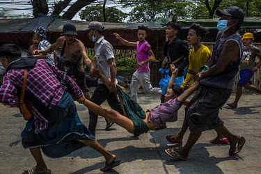 People carry a man wounded by a gunshot after military and police joint security forces opened fire on anti-coup protestors during a crackdown in Hlaingtharyar industrial zone on the outskirts of Yang...