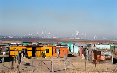 Tin shacks with power stations' smoke stacks beyond.