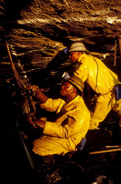 Gold miners drilling at the rock face.