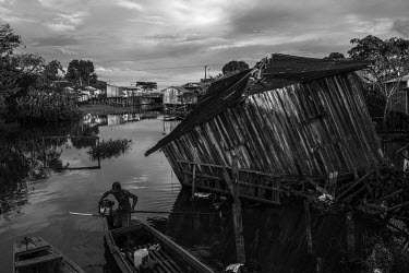 A fisherman unloads his boat in a stream next to a collapsed house. All the residents of this region known as 'Baixao' (lower part of the city) have been removed from their homes because of the rising...