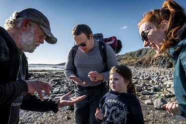 The Farndon family inspect small pyritised ammonites during a guided fossil tour with geologist Paddy Howe on the beach at Lyme Regis. The Farndons came fossil hunting after their daughter, Ellie, hea...