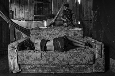 A woman lies on a sofa as a police officer searches for drugs in a shack used by crack cocaine users on Olarias street, in one of the most violent neighbourhood in Altamira.The construction of the Bel...