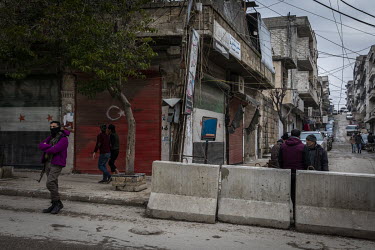 People walk past a shuttered shop front painted with the flags of Turkey and the Free Syrian Army in downtown Afrin.