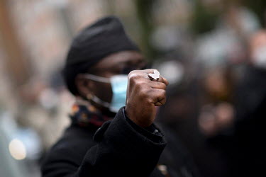 A member of the local African diaspora raises a fist, on which he is wearing a ring in the shape of the African continent, during a demonstration against colonial history, the politics of colonialism...