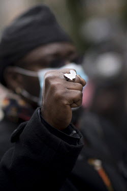 A member of the local African diaspora raises a fist, on which he is wearing a ring in the shape of the African continent, during a demonstration against colonial history, the politics of colonialism...