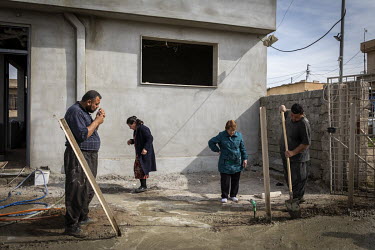 Sisters Amina (right) and Mohinta Sha'ana watch as a team of Shiite Muslim Shabak workers continue with the rebuilding of their house in a Christian area of Bartella.   Prior to being overrun by ISIS...