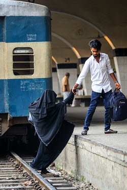 A man helps a woman on to the platform after crossing the tracks at Kamalapur Railway Station (officially known as Dhaka railway station).