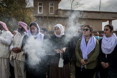 Yazidi women burn incense as they wait for the funeral procession for the 103 Yazidis from the village of Kocho killed by ISIS in 2014 to pass by. Having been exhumed from the mass graves where they w...