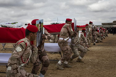 Iraqi soldiers act as pallbearers, carrying coffins during a funeral procession for 103 Yazidis killed by ISIS in the village of Kocho in 2014. Having been exhumed from the mass graves where they were...