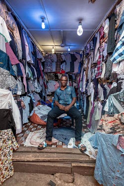 Second hand clothes salesman Oppong Antwi (50) in his stall in Kejetia market (Kumasi Central Market). Antwi says the business can be a gamble. Each 55kg bale of reject clothes contains around 400 shi...