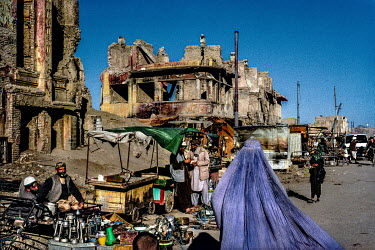 A market set up on a road lined with buildings heavily damaged during the Afghan-Soviet war.