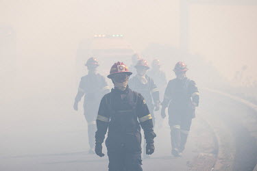 Fire fighters walk through thick smoke as they battle a wildfire on the edge of Cape Town.