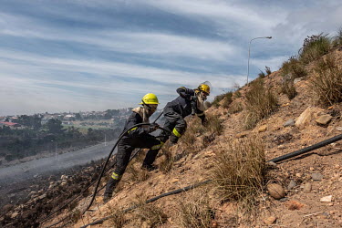 Fire fighters extinguish embers from a wildfire on the egde of Cape Town.