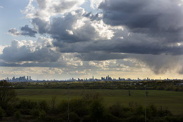 A field on the edge of east London with London's high rise buildings stretching from the the BT Tower on the right through the City, the Shard and Canary Wharf on the left.