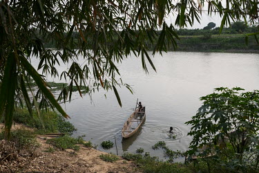 A child paddles a canoe as a man swims on the edge of the village of Dekanme along the Oueme River. Dwindling fish stocks are one of many factors that accelerate pressure on forests, as people must in...