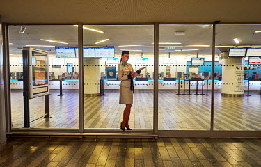 A cardboard cutout fugure welcomes people to an almost empty train ticket sales office that would normaly be busy.