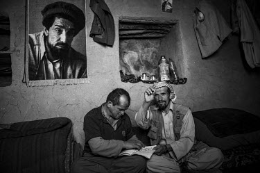 Two miners examine emeralds extracted from a makeshift emerald mine in the Panjshir Valley. On the wall behind them is a rug woven with the image of Ahmad Shah Massoud.