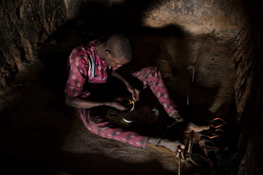 A patient whose has had his ankles shackled sits in a small dark cell eating food from a plastic container at the Emmanuel Rehabilitation Centre for Mentally Ill People which is run by Miss Mojisola A...