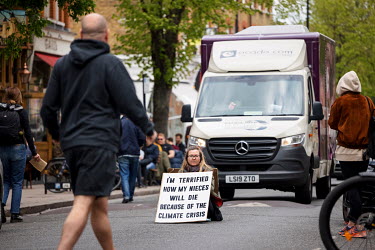 A delivery van is stopped by a lone woman climate protestor sitting in the middle of Abbeyville Road in Clapham during an Extinction Rebellion 'Rebellion of One' action.