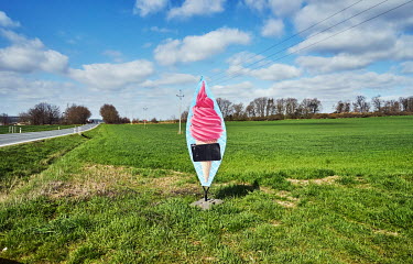 An ice cream advertisement in the field at the side of a road.