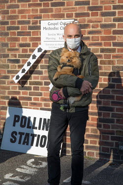 A man and his dog in a queue of people outside a polling station during voting for the London Mayor and other local offices on 6 May 2021. The current mayor, Sadiq Khan, held on to his office in a win...