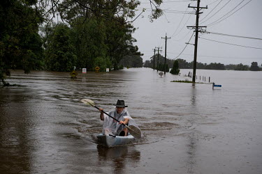 A man paddles a plastic boat in Windsor where over the previous weekend, the Hawkesbury River rose rapidly by more than 30 feet.