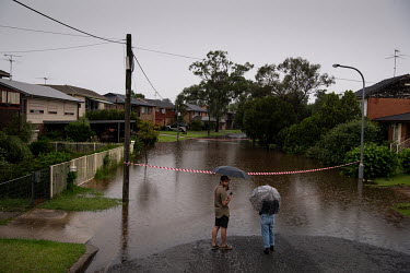 A couple stand at the edge of the water on a flooded road in Windsor where over the previous weekend, the Hawkesbury River rose rapidly by more than 30 feet.